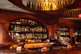 Interior of Bar Raval in Toronto, Canada with wood walls, tin ceilings and a stocked bar.