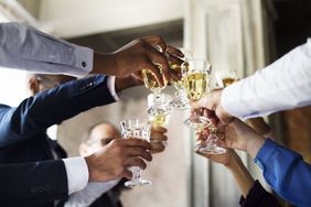 A group of people toasting wine glasses at a wedding. 