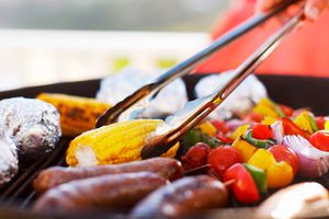 A person grilling vegetables and meats