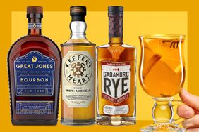 Bottles of Great Jones Bourbon, Keeper’s Heart Irish + American Blend, Sagamore Spirit Small Batch Rye and a hand holding a hot toddy on a mustard colored background. 