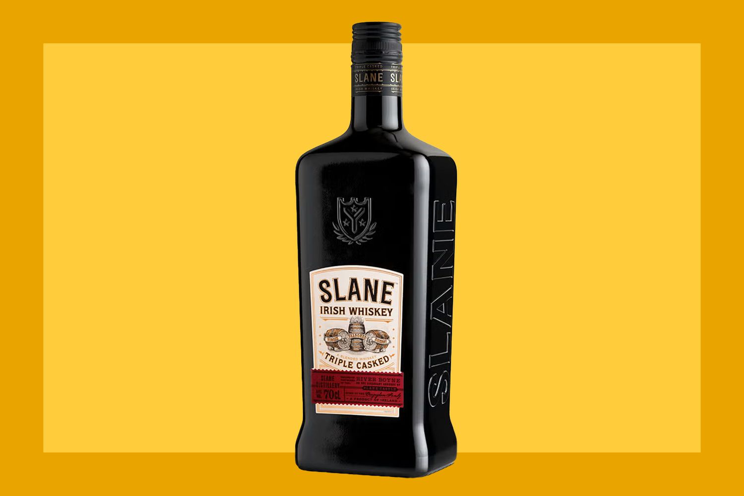 A bottle of Slane Irish Whiskey on a mustard colored background. 