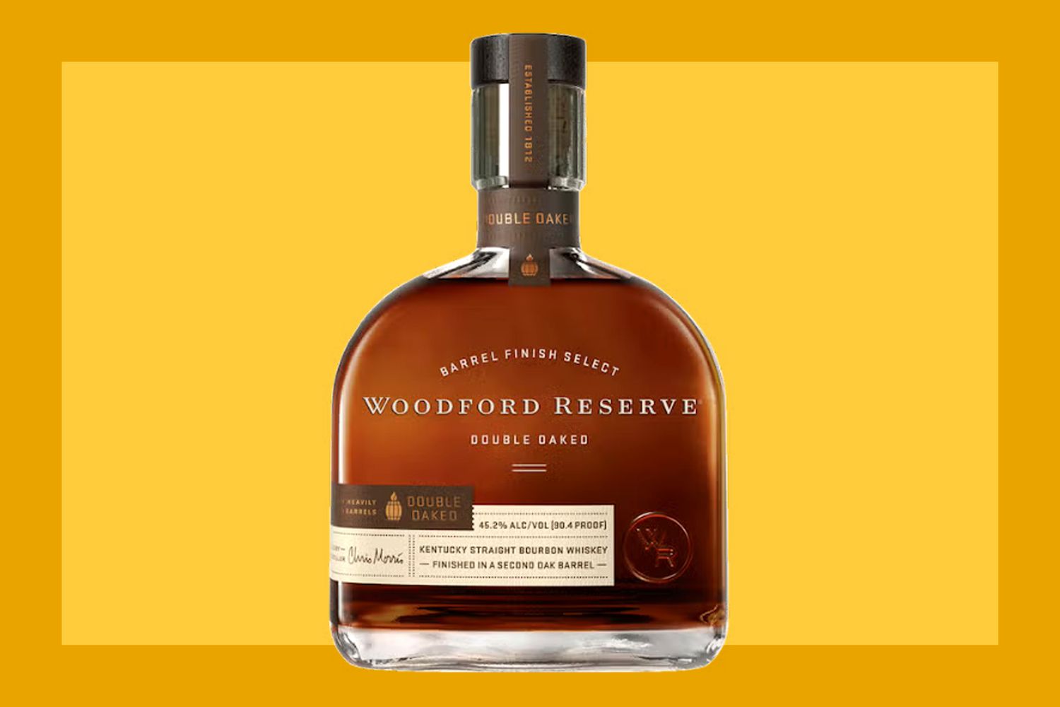 A bottle of Woodford Reserve Double Oaked Bourbon on a mustard colored background. 