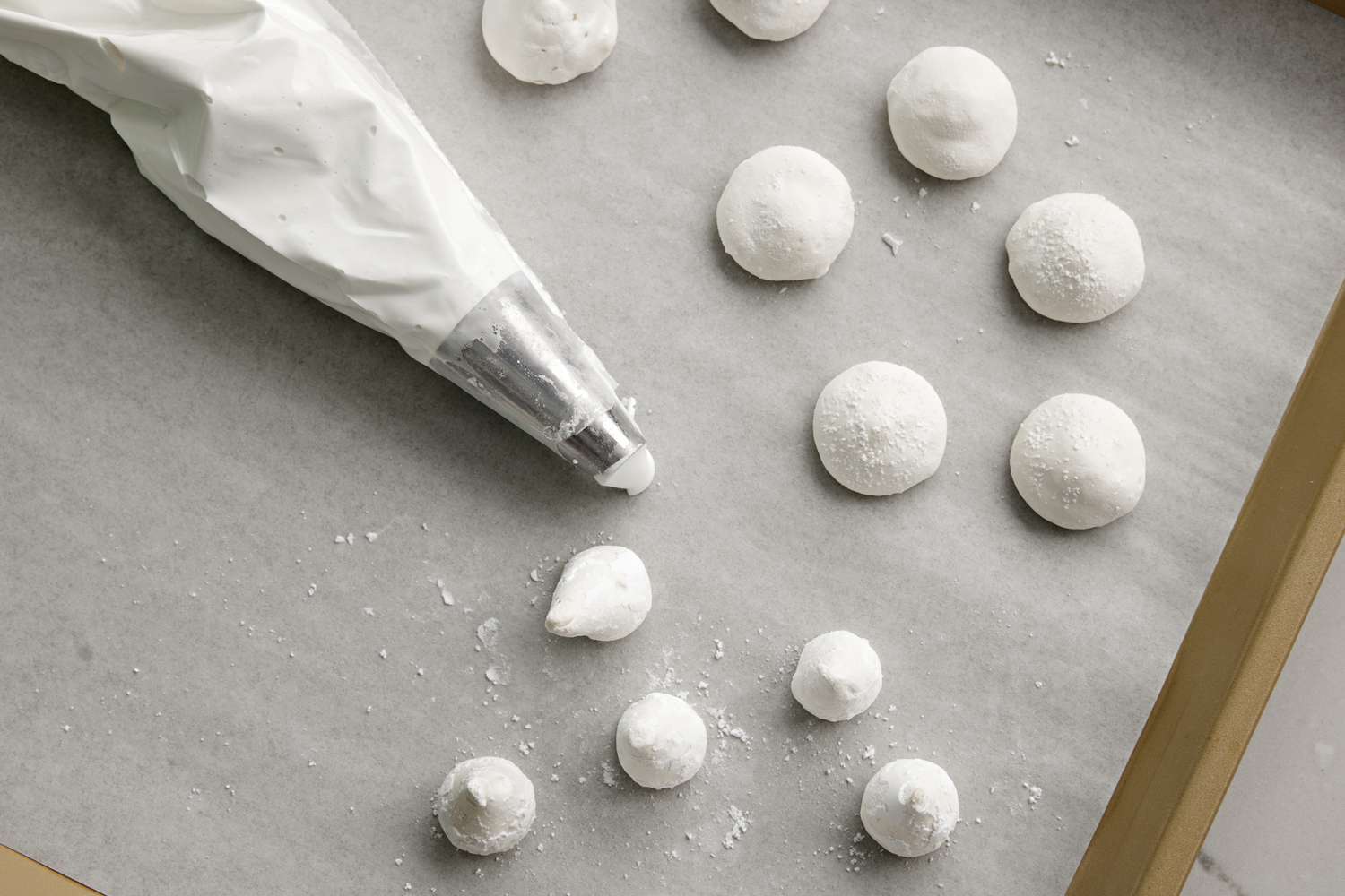 Pipe wide meringue kisses for mushroom caps and slender cone shapes for stems. Press the piping bag longer before stopping and pulling up for caps; pipe and pull up quicker for slim stems.