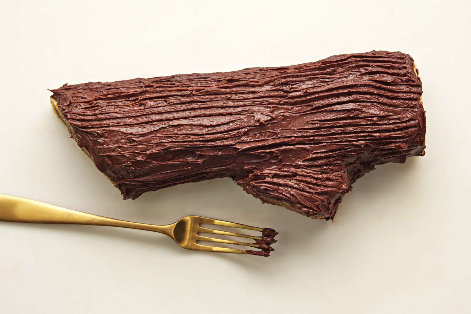 Drag tines of a fork over the frosted cake to carve thin bark lines. You can also use a small offset spatula or table knife for a wide bark look.