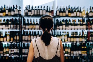 A person faces a large display of wine