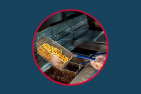 A person frying french fries in a commercial kitchen.