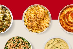 Bowls of stuffing, mac and cheese, mashed sweet potatoes, green bean casserole and mashed potatoes on a red and cream colored background. 