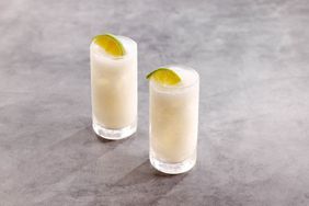 Coconut Lime Horchata in two highballl glasses with lime wedge garnish, on grey marble background