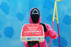 A Squid Game guard holding a Domino's Emergency Pizza. 