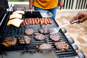 A person flips burgers on a grill