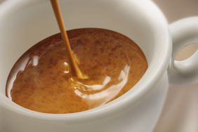 Espresso being poured into a white coffee cup