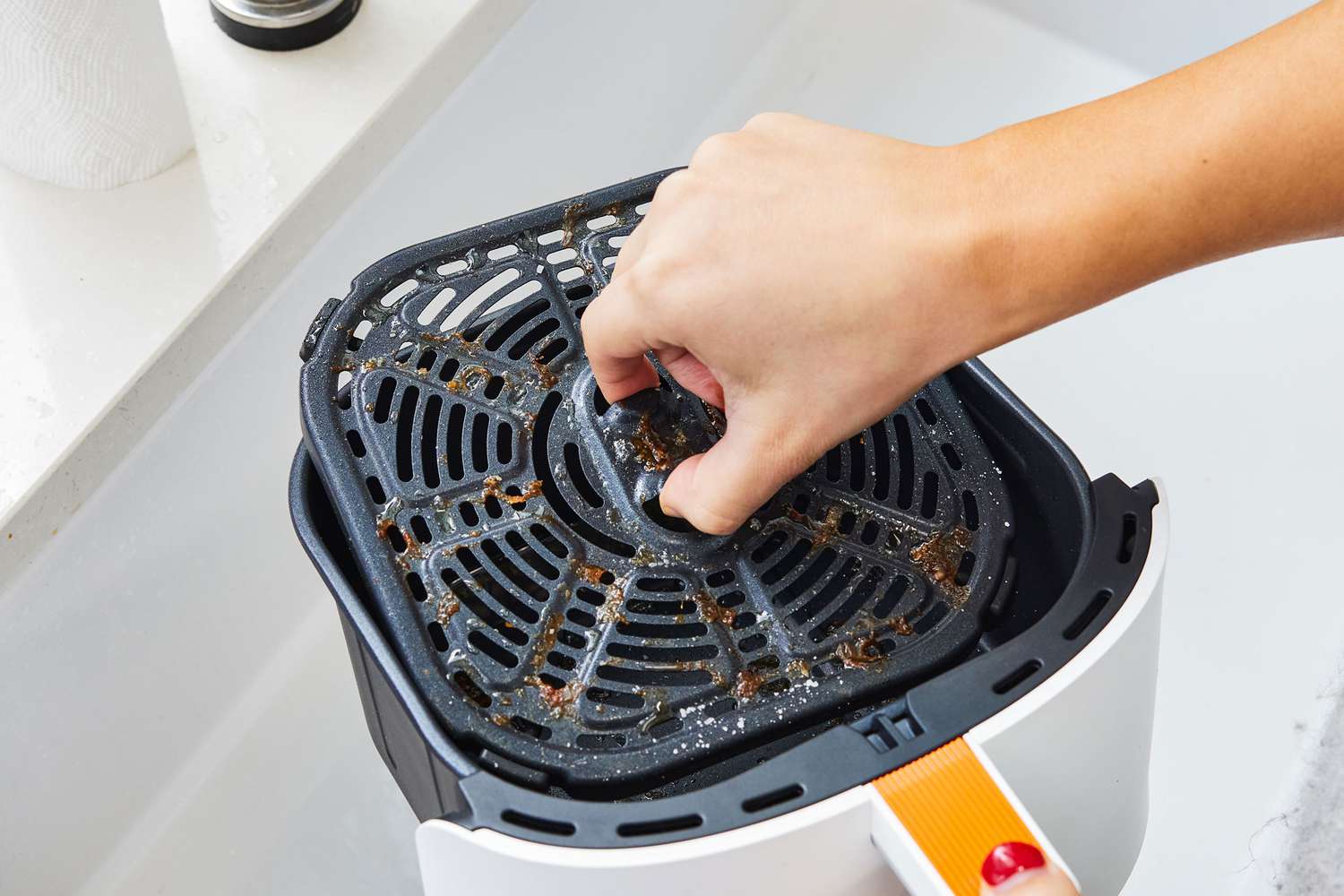 Hand lifting a dirty tray from the Cosori 4-Quart Smart Air Fry basket