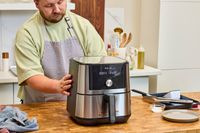 A person touches the sides of the Instant Vortex Plus 6QT XL Air Fryer