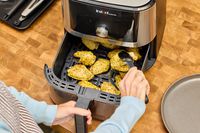 A person cooks chicken in the Instant Vortex Plus 6QT XL Air Fryer