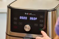 A person presses the start button on the Instant Vortex Plus 6QT XL Air Fryer