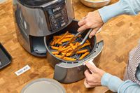 A person removes french fries from the Ninja 4-Quart Air Fryer