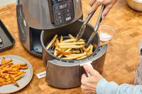 A person removes french fries from the Ninja 4-Quart Air Fryer