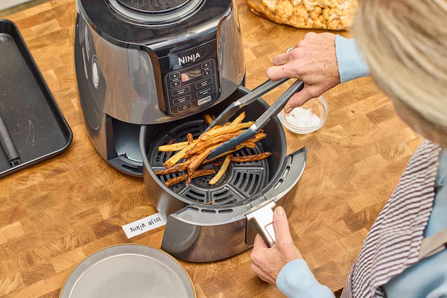 A person removes fries from the Ninja 4-Quart Air Fryer