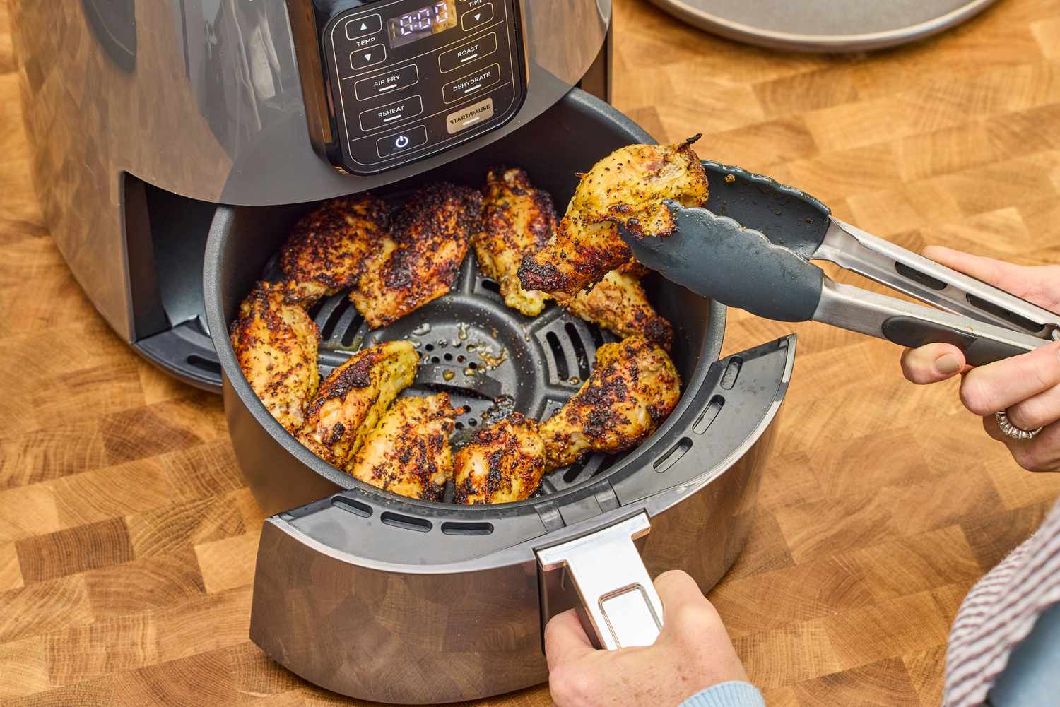 A person removes a chicken wing from the Ninja 4-Quart Air Fryer