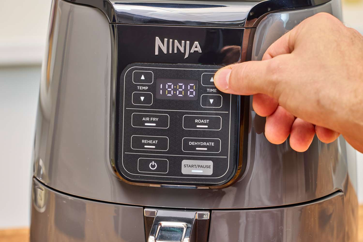 A person presses a button on the Ninja 4-Quart Air Fryer