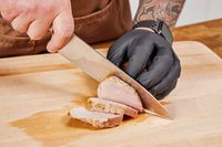 A person slicing meat cooked in the Breville the Smart Oven Air Fryer