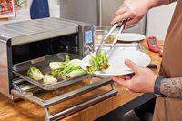 A person plating vegetables cooked in the Breville the Smart Oven Air Fryer