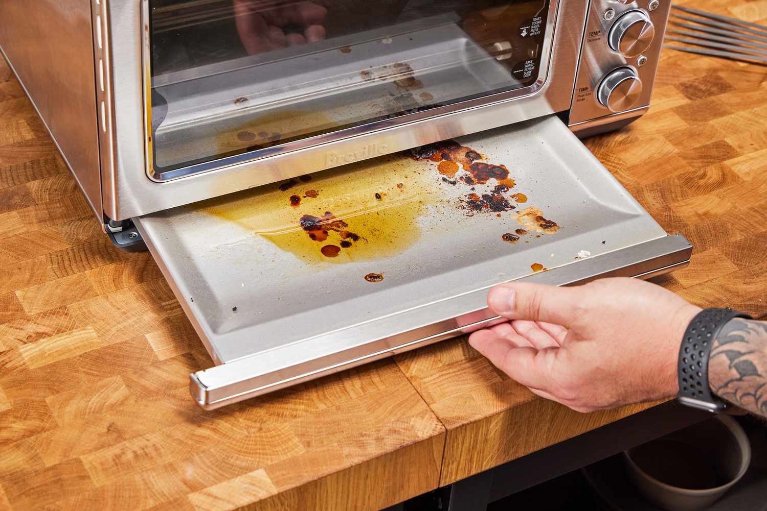 A hand removing a dirty section from the Breville the Smart Oven Air Fryer