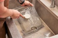 A person cleaning the rack from the Breville the Smart Oven Air Fryer in a sink