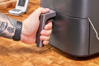 A hand holding the handle of the COSORI TurboBlaze 6.0-Quart Air Fryer