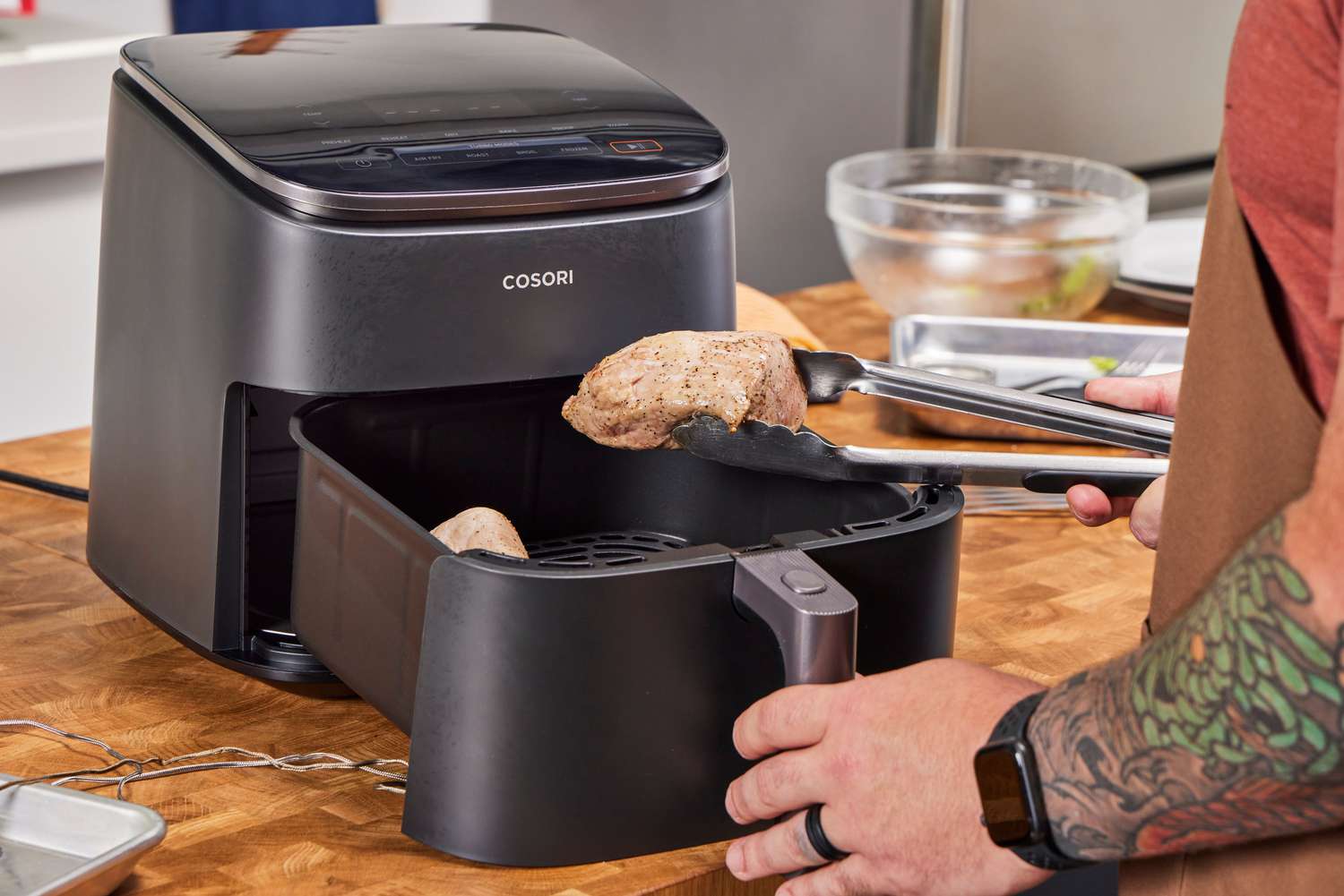 A person removing cooked meat from the COSORI TurboBlaze 6.0-Quart Air Fryer