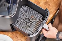 A hand holding the dirty basket of the COSORI TurboBlaze 6.0-Quart Air Fryer