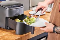 A person placing vegetables cooked in the COSORI TurboBlaze 6.0-Quart Air Fryer onto a plate