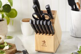 A set of Henckels' knives in a woodblock on a kitchen counter