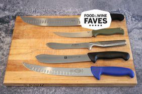 Five butcher knives displayed on a wooden cutting board