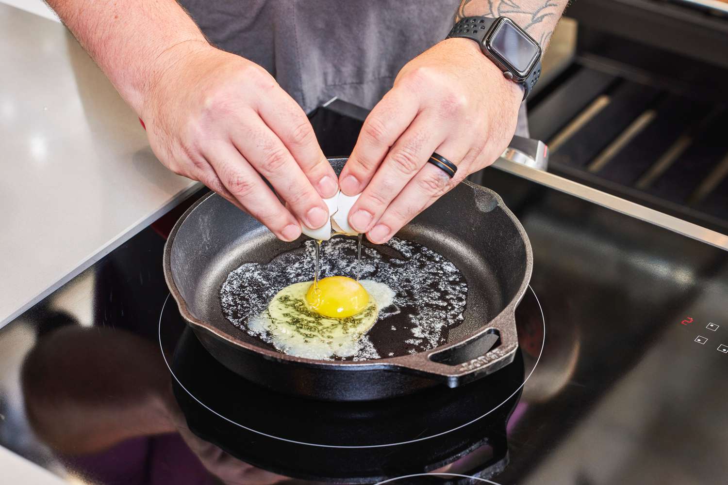 A person cracks an egg into the Lodge Cast Iron Skillet