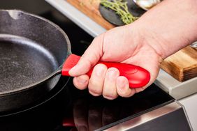 A person holds the handle of the Lodge Cast Iron Skillet 