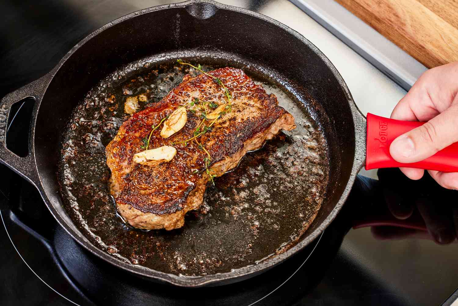 A person cooks meat in the Lodge Cast Iron Skillet