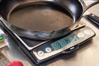 Lodge Blacklock Triple-Seasoned Cast Iron Pan being weighed on a kitchen scale