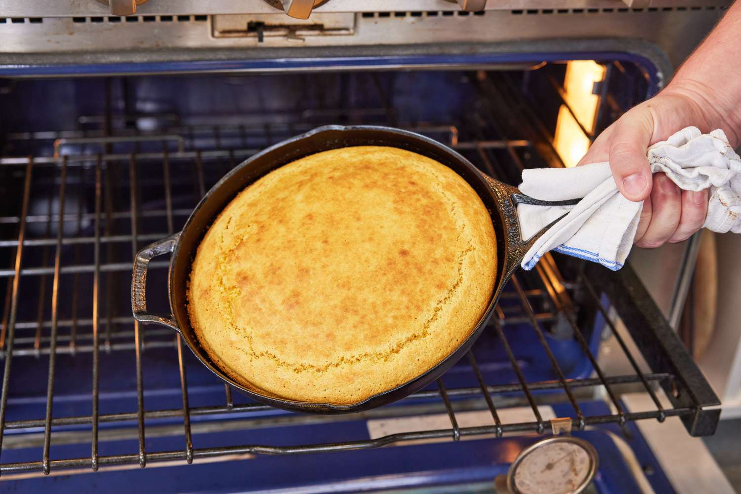 Person holding with cooked cake in Lodge Blacklock Triple-Seasoned Cast Iron Pan - 10 1/4” Diameter