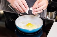 A person cooks an egg in the GreenPan Nova Ceramic Nonstick 10-Piece Cookware Set pan