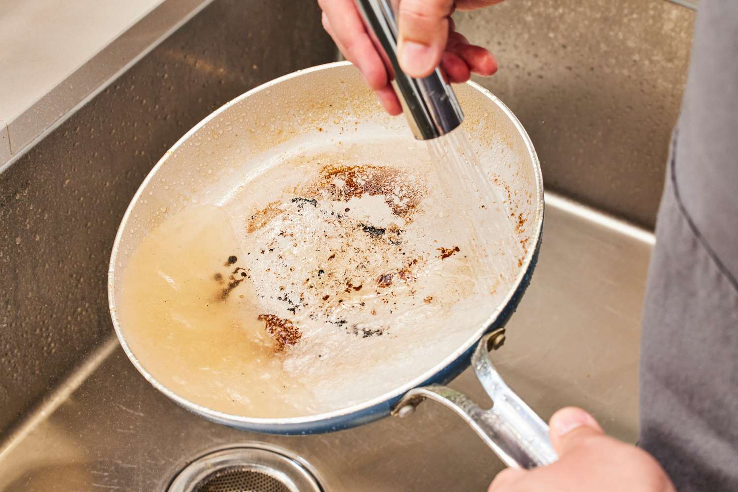 A person rinses the GreenPan Nova Ceramic Nonstick 10-Piece Cookware Set with water