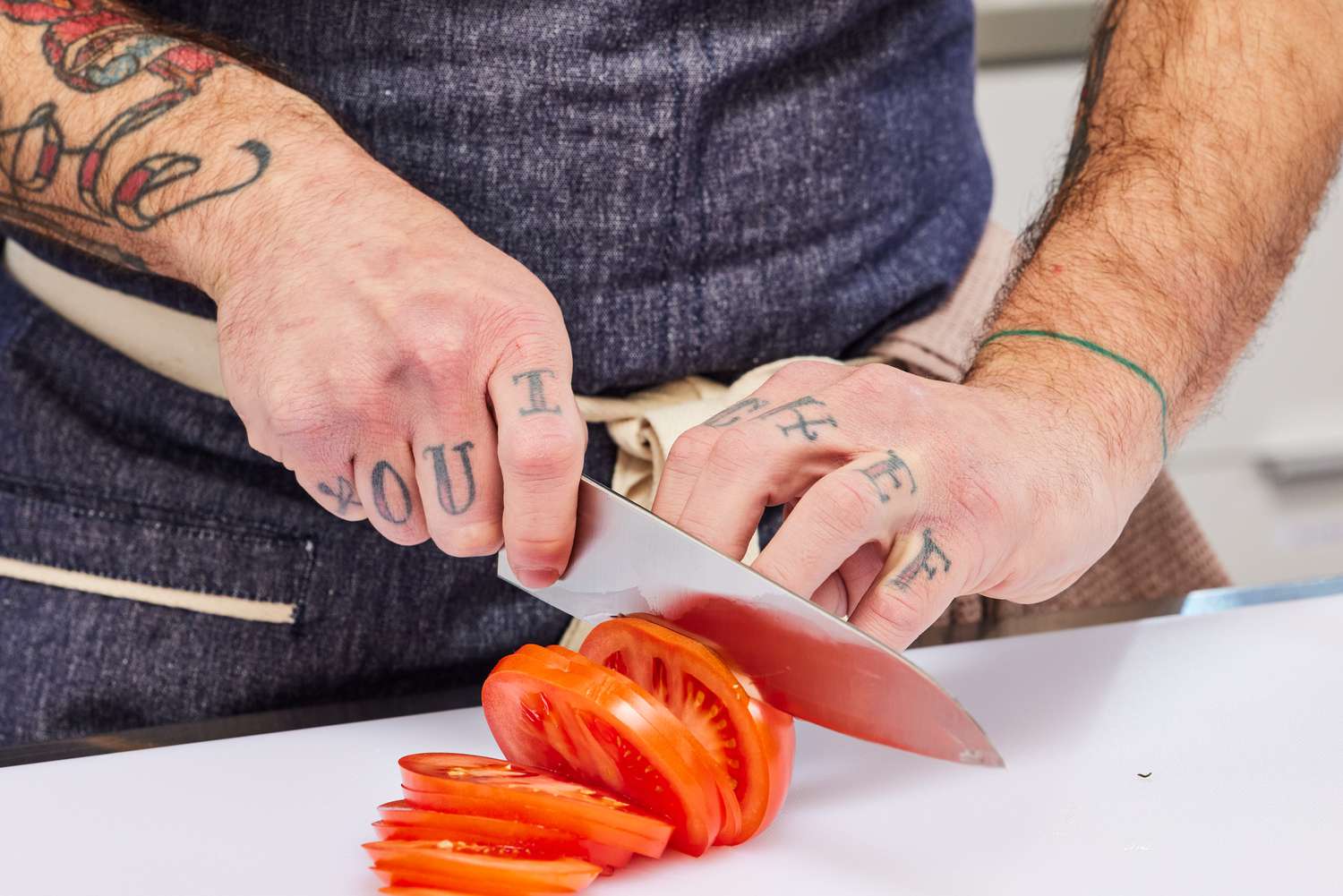 Hands slicing a tomato with a Mercer MX3 8.25-Inch Chef Knife