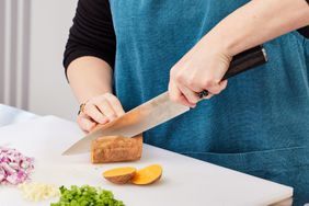 Hands slicing a sweet potato lengthwise with a Paudin Pro 8-Inch Chef's Knife