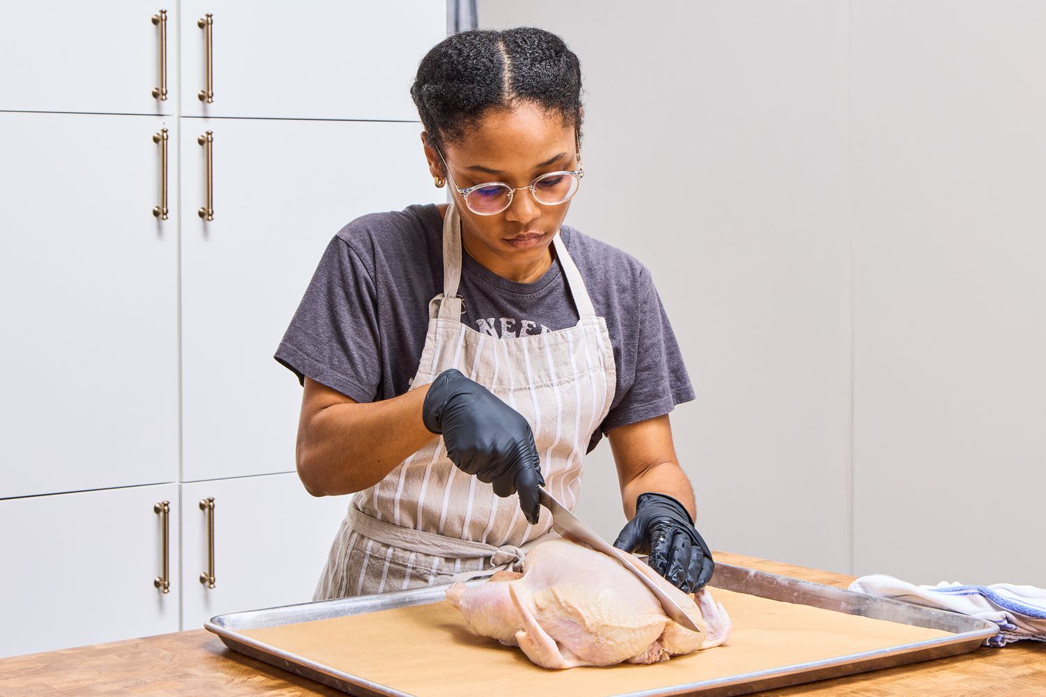 A person cuts into a chicken with the Global Classic 8-Inch Chef's Knife