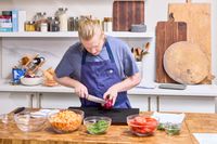 A person slices onion with the Global Classic 8-Inch Chef's Knife in a kitchen