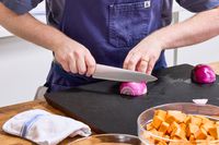 A person slices onion with the Global Classic 8-Inch Chef's Knife