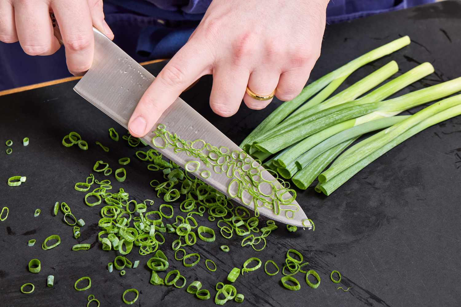 A person slices scallions with the Global Classic 8-Inch Chef's Knife