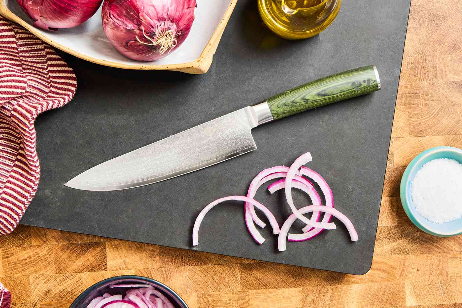 The HexClad 8 Inch Damascus Steel Chef’s Knife on a cutting board with sliced onions