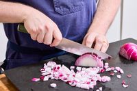 A person chops an onion with the HexClad 8 Inch Damascus Steel Chef’s Knife