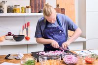 A person chops an onion with the HexClad 8 Inch Damascus Steel Chef’s Knife